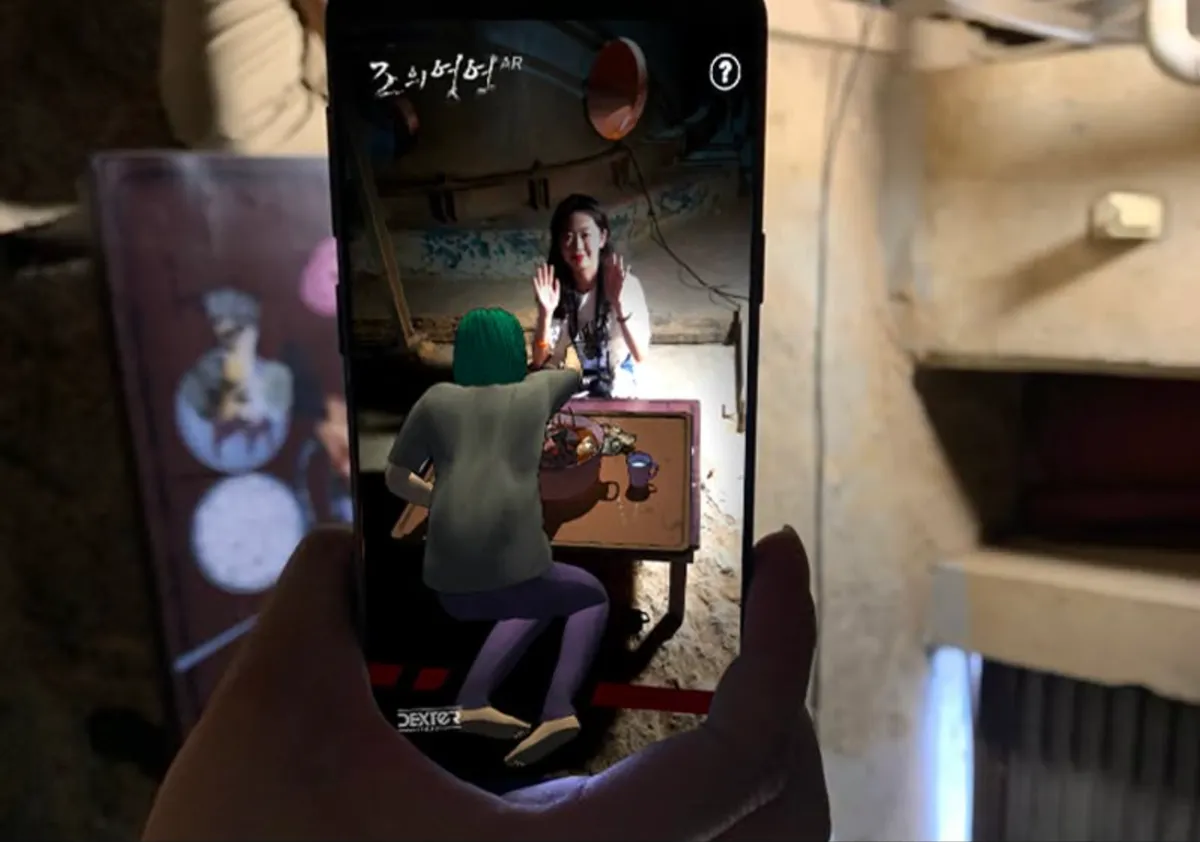 An AR character appearing at a table on a phone held up in The Tide exhibition